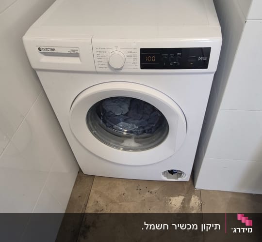 מכונת כביסה מותקנת בפינת חדר עם חוט חשמל